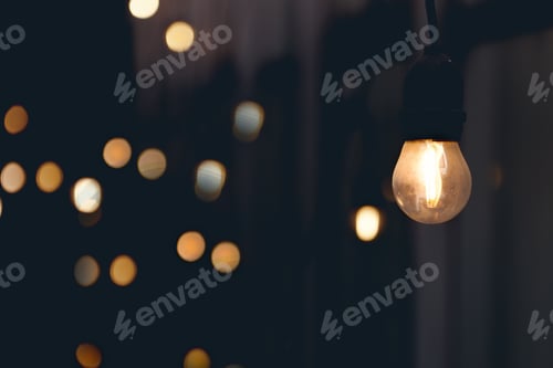 Preview: Glowing Light Bulb Against Dark Background With Bokeh