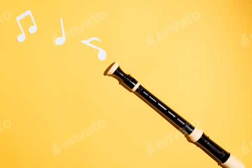 Preview: Musical black flute and notes cut from paper on a yellow background. Flat lay