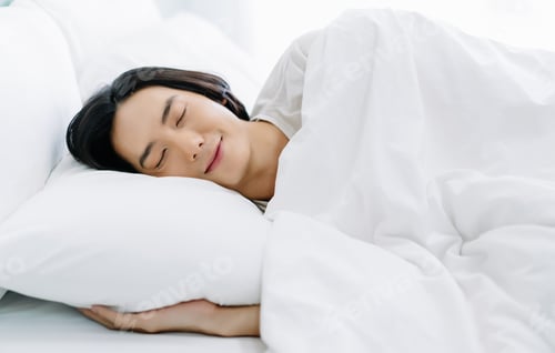 Preview: Side view of young Asian man smiling while sleeping in his bed and relaxing in the morning.