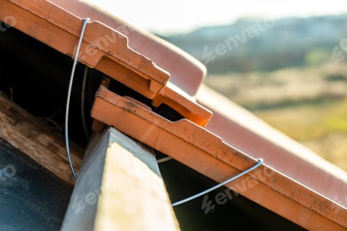 Preview: Closeup of metal montage anchor for installation of yellow ceramic roofing tiles