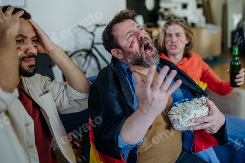 Preview: Nervous football fans friends watching German national team in live soccer match on TV at home