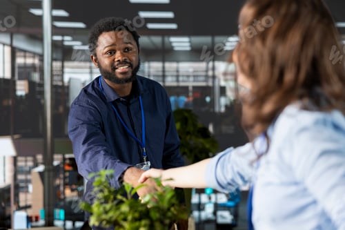 Visualização: Líder de equipe afro-americano dando as boas-vindas ao novo contratado no escritório