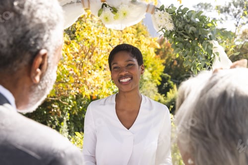 Preview: Happy biracial female marriage officiant and senior couple during wedding in sunny garden
