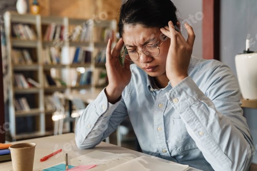 Preview: Image of tired asian man with headache rubbing his temples