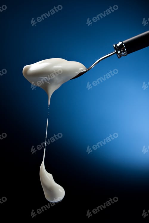 Preview: Spoon with natural yogurt over blue background.
