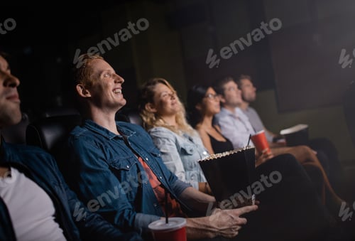 Preview: Happy young friends watching movie in cinema.