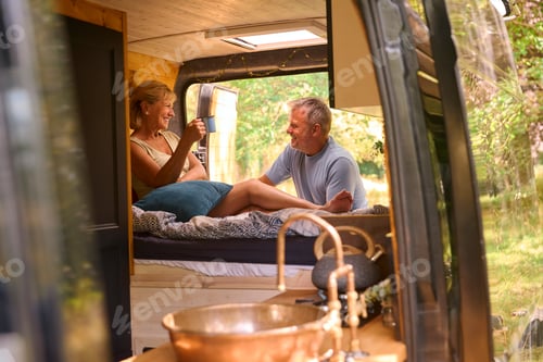 Preview: Senior Couple Camping In Countryside Relaxing Drinking Coffee Inside RV