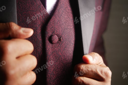 Preview: Elegant man adjusts his stylish burgundy suit in a formal setting