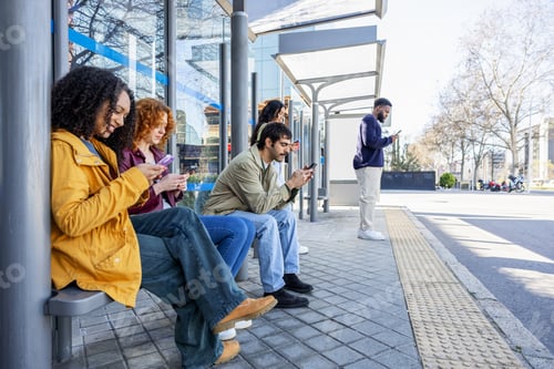 Preview: Diverse group of young adults immersed in their phones at a city bus stop