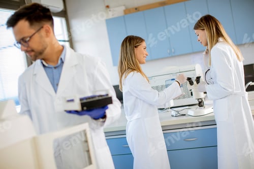 Preview: Researcher in protective workwear standing in the laboratory and analyzing liquid samples