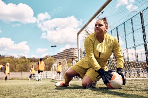 Preview: Female goalkeeper catching ball while defending a goal on soccer training at the stadium.
