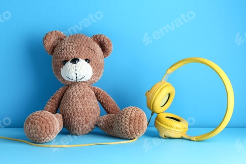 Preview: Baby songs. Toy bear and yellow headphones on light blue background
