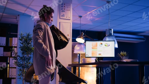 Preview: Business woman getting up to leave office at night