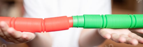 Preview: anti stress sensory pop tube fidget toy in kid's hands. little happy child boy plays with poptube