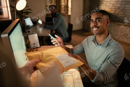 Preview: African American businessman receiving a delivery while working in the office.
