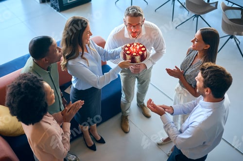 Visualização: Equipe comemorando o aniversário de um colega do sexo masculino em um escritório multicultural de plano aberto com bolo