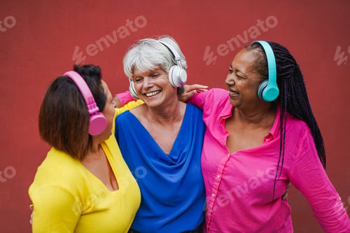 Preview: Happy senior women having fun listening music with wireless headphones outside