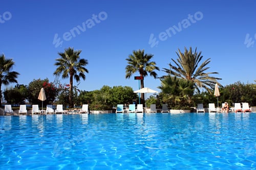 Preview: Saltwater pool, palm trees, arm-chairs and beach umbrellas in the southern resort