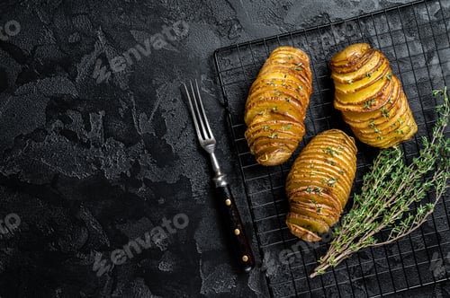 Preview: American traditional Homemade Hasselback Potato with Fresh Herbs. Black background. Top view.