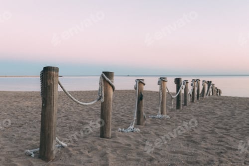 Preview: A row of wooden posts with rope tied to them on a beach