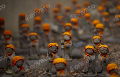 Preview: Close up of small brown Buddhist Jizo, Japanese stone statues, wearing orange hats, at Daienji,
