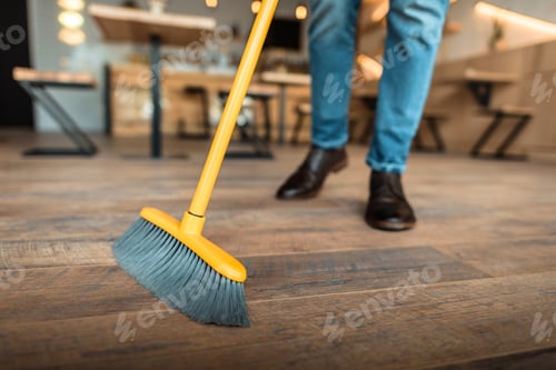 Preview: cropped view of african american worker sweeping with broom in coffee shop