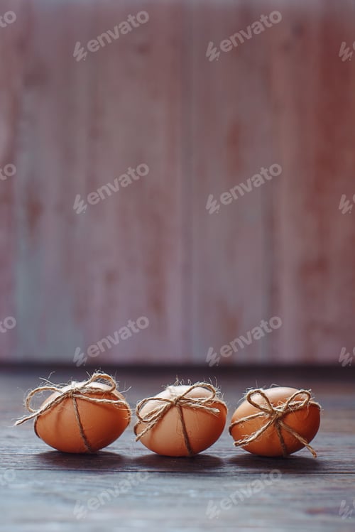 Preview: Easter beige eggs decorate with rope on brown wooden background