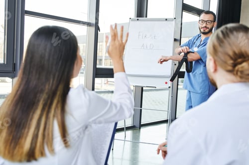 Preview: medical instructor with compressive tourniquet standing at flip chart and looking at student asking