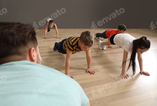 Preview: Cute little children and trainer doing physical exercise in school gym. Healthy lifestyle