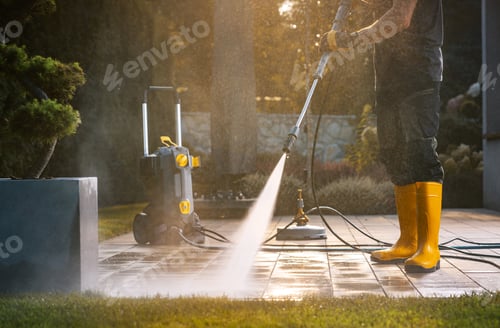 Preview: A Person Power Washing a Patio With a Pressure Washer in a Sunny Outdoor Setting