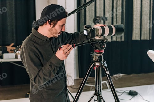 Preview: Side view of cameraman working in photo studio