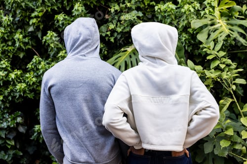 Preview: Rear view of african american couple wearing white and grey hooded sweatshirts in garden