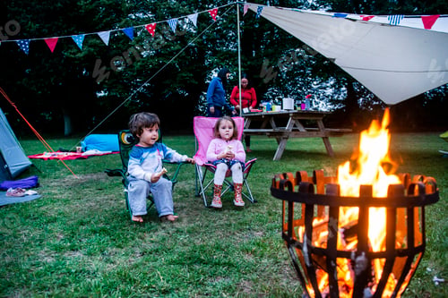 Preview: Children relaxing in front of bonfire, parents in background