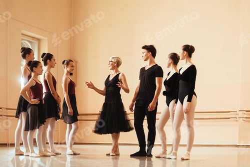Preview: Mature ballet instructor holding a class to group of ballet dancers in a studio.