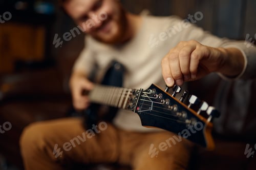Preview: Young man guitarist tune guitar before playing