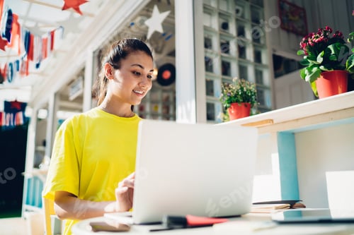 Preview: Smiling young woman using laptop in cafe