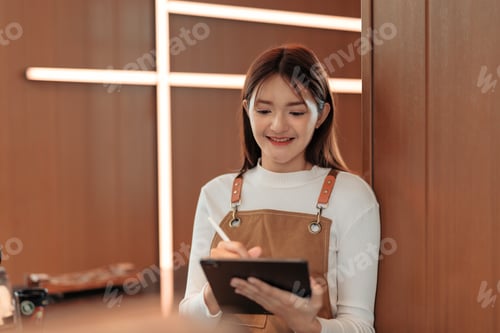 Preview: Young barista taking orders using digital tablet in cafe