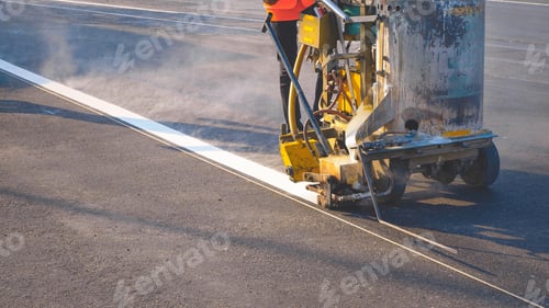 Preview: Low section of road worker with marking machine is painting traffic white line on asphalt road