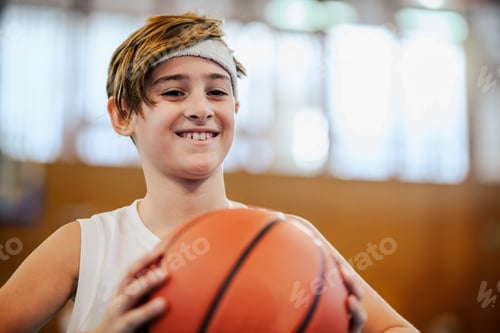 Preview: Close up of junior basketball player posing with ball and smiling.