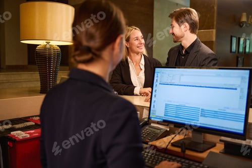 Preview: Hotel administrator checking in couple standing at reception desk