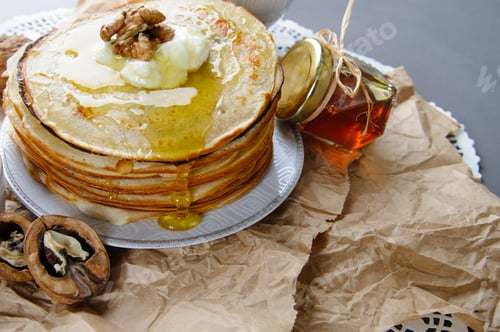Preview: Stack of pancakes on a paper napkin, served with honey and walnu