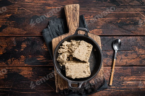Preview: Halva with sunflower seeds and honey in pan. Wooden background. Top view