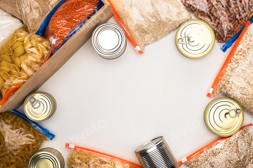 Preview: top view of cans and groats in zipper bags with wooden box on white background, food donation