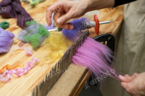 Preview: Hands crafting colorful wool roving on wooden blending hackle