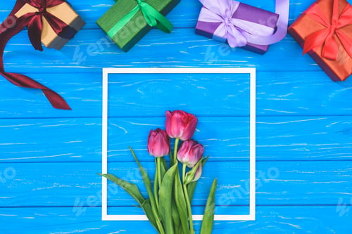 Preview: top view of gift boxes and pink tulips in frame on blue table