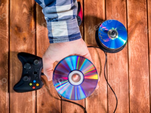 Preview: hand choosing a video game to play compact disk on the wooden table