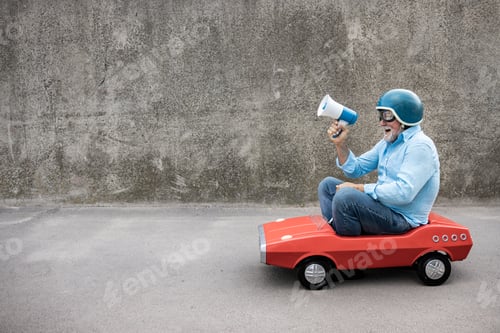 Preview: Funny businessman driving retro pedal car outdoor
