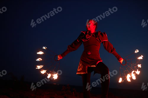 Preview: Performer with fire fans outdoors at night