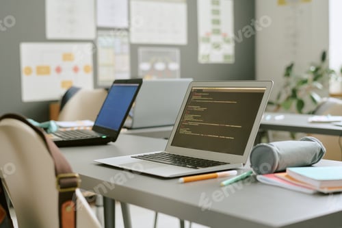 Preview: Empty Classroom Showing Laptops with Code Displayed on Desks during Lesson