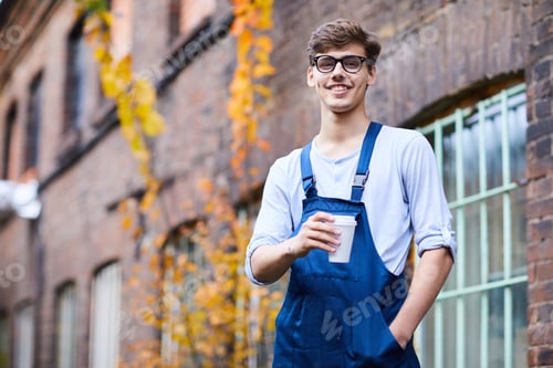 Preview: Handsome factory worker drinking coffee outdoors